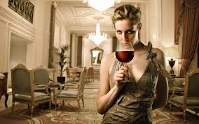 elegant looking woman drinking a glass of red wine surrounded by new stuff.